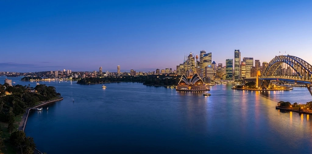 Sydney skyline at dusk across the harbour with city lights